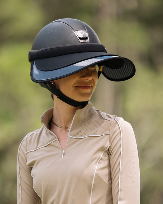 Person wearing a black riding helmet with a visor outdoors